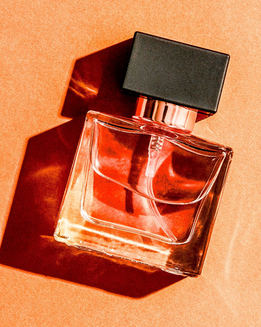 Chanel L'Ombre hero shot — bottle on orange with deep shadow